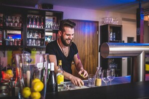 A bartender preparing drinks at a bar with shelves of glassware and bottles. - Engel Hotel und Diner (Aulendorf)