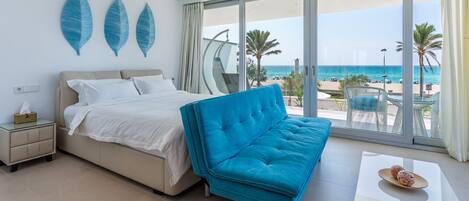 Une chambre moderne avec un grand lit, un canapé bleu et une vue sur la plage.