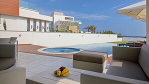 A modern outdoor pool area with a hot tub, seating, and a fruit bowl. - Pearl Beachfront Villa (Ayia Napa)