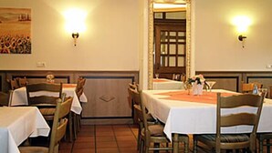 Un restaurant avec des tables et des chaises, un tableau accroché au mur et deux lampes fixées au mur.