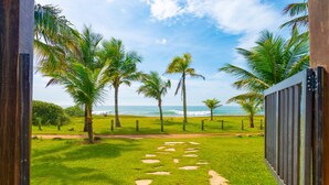 Ein Pfad, der zu einem Strand mit Palmen und Blick aufs Meer führt.