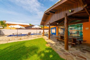 An outdoor patio area with stone flooring, wooden benches, and umbrellas.