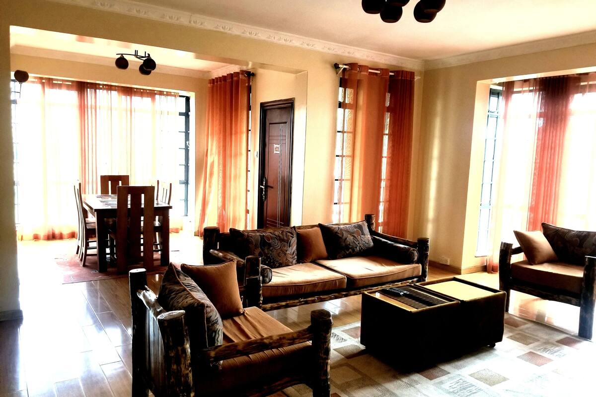 A spacious living room with a sofa set, a coffee table, and a dining area with a table and chairs.