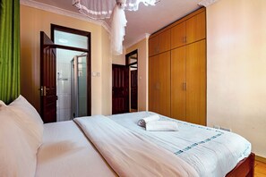 Relax in a serene space with a comfortable bed, a stylish wardrobe, and a convenient mirror.