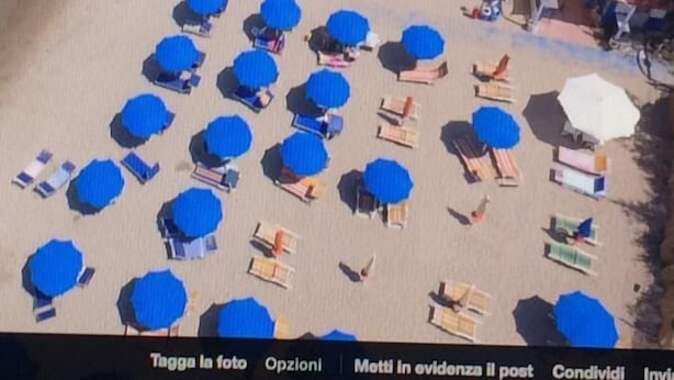 An aerial view of a beach with numerous umbrellas and sun loungers.