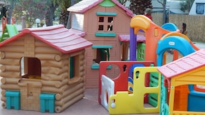 A children's play area with various colorful play structures, including a log cabin and a slide.