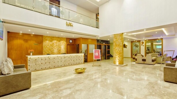 A spacious lobby with a reception desk, seating area, and a staircase leading to an upper level. - R G Hotels and Resort (Malur)
