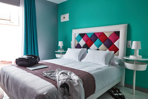 A hotel room with a bed, a nightstand, a lamp, a suitcase, and a bag on the bed. - Hotel Freedom (Madrid)