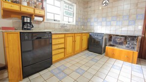 Une cuisine avec des meubles de rangement en bois, un lave-vaisselle, une cuisinière et une machine à café.
