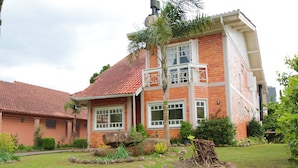 Une maison à deux étages, avec une façade en briques rouges, un toit en tuiles et un petit balcon.