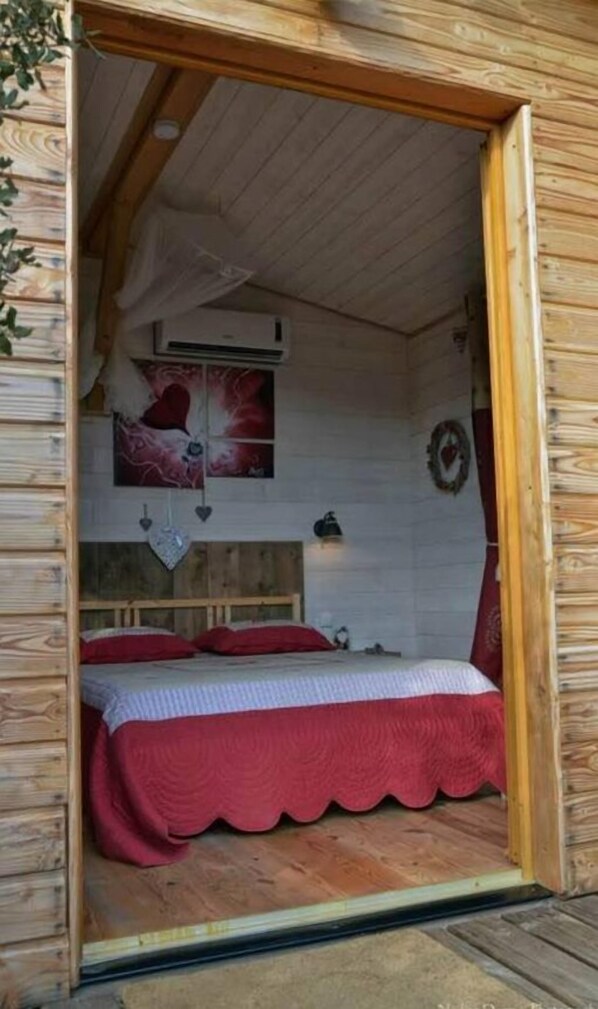 Un dormitorio de cabaña acogedor con cama, aire acondicionado de pared y un adorno decorativo.