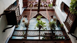 A traditional courtyard with ornate wooden lattice railings and hanging plants. - Emerson Spice Hotel (Zanzibar Town)