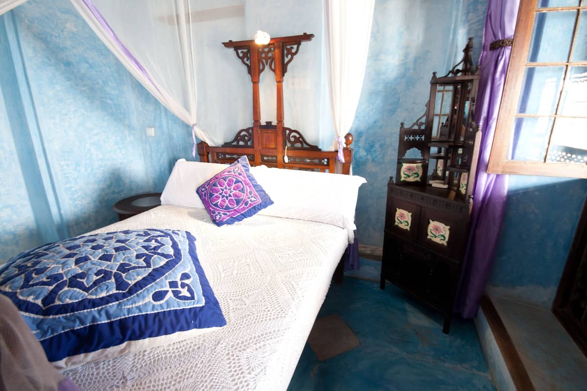 A bedroom with a bed, a wooden headboard, a nightstand, and a dresser.