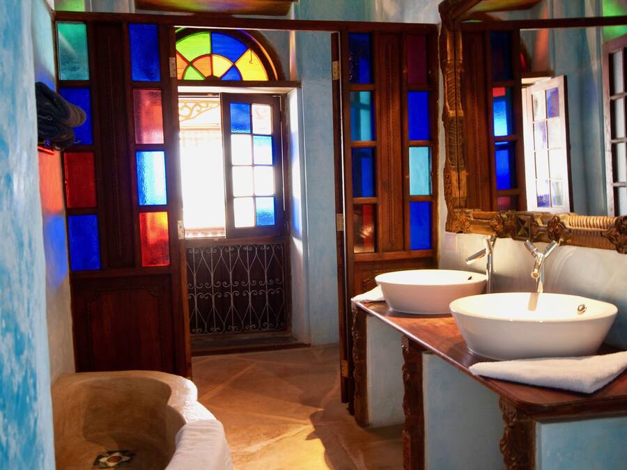 A bathroom with a bathtub, two sinks, and stained glass windows.