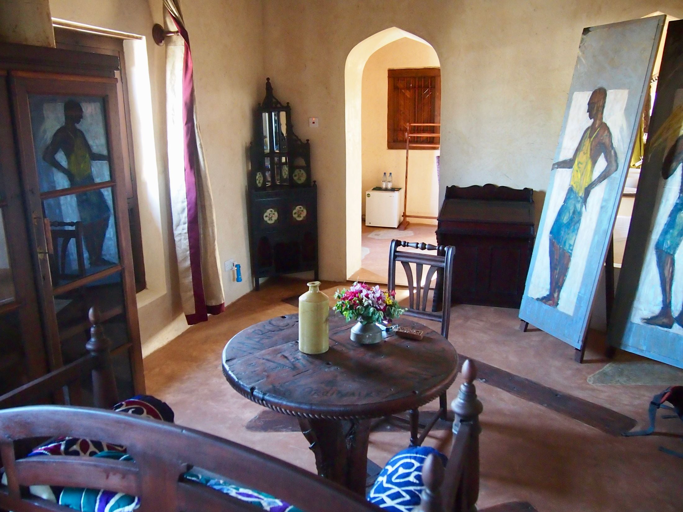 A room with a round wooden table, a cabinet, and a painting.
