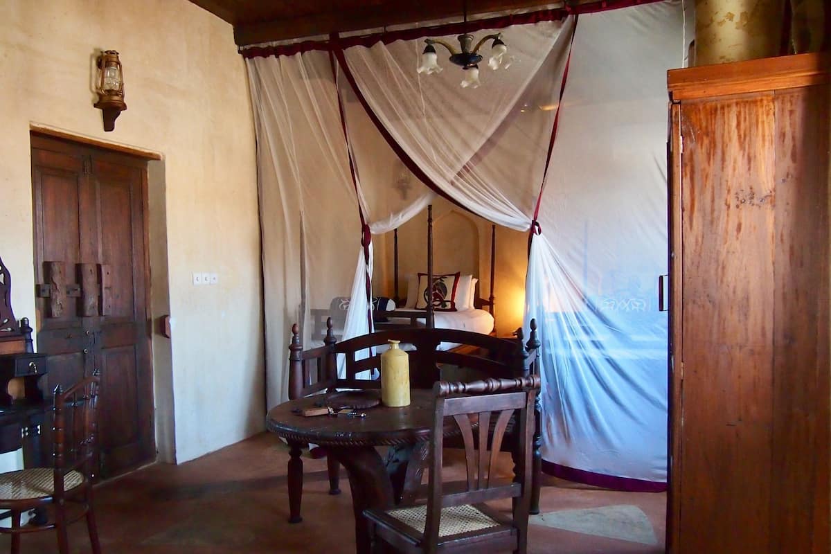 A room with a four-poster bed, wooden furniture, and a canopy.