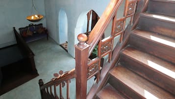 Una escalera de madera con barandales elaborados y un banco al final.