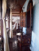 Un porche de madera con una mesa, sillas, una hamaca y un armario de madera.
