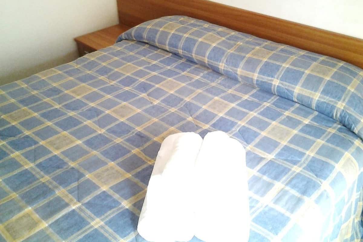A bed with a blue and yellow checkered bedspread and a matching pillow.