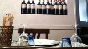 Ein Essbereich mit Tisch für zwei Personen, einem Weinschrank darüber und einem Fenster im Hintergrund.