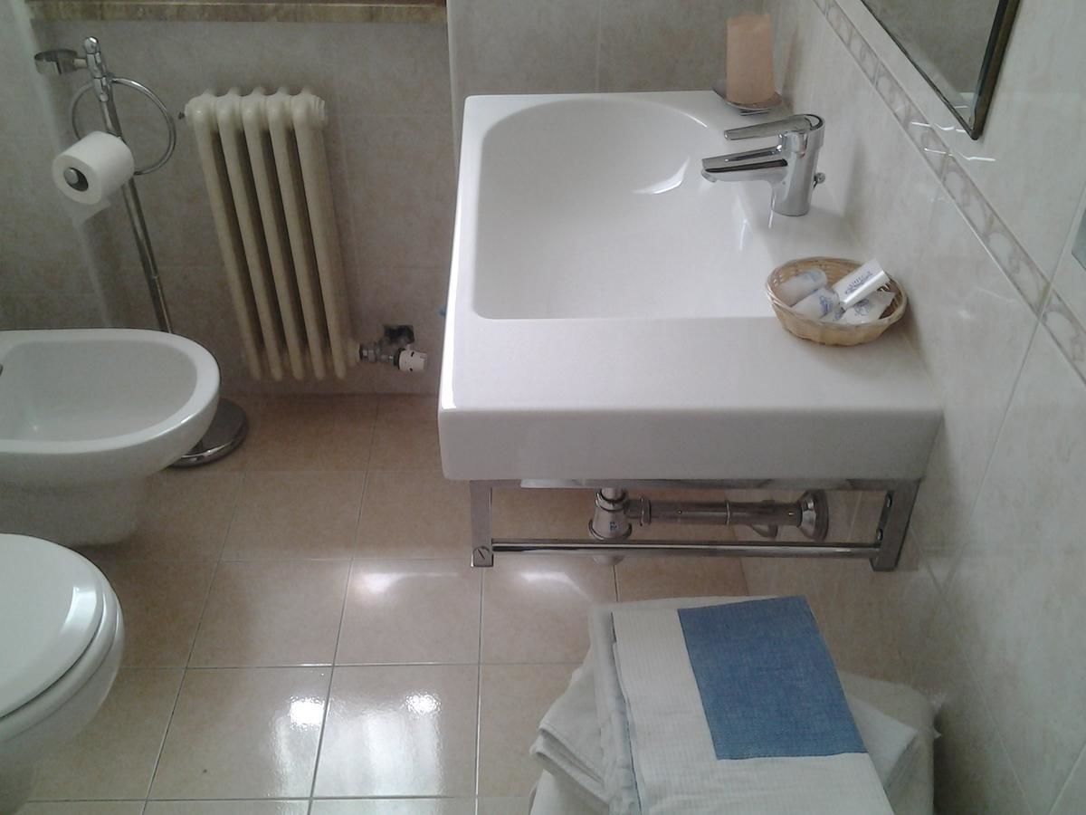 Casa de banho com sanita, bidé e lavatório com espelho em cima.