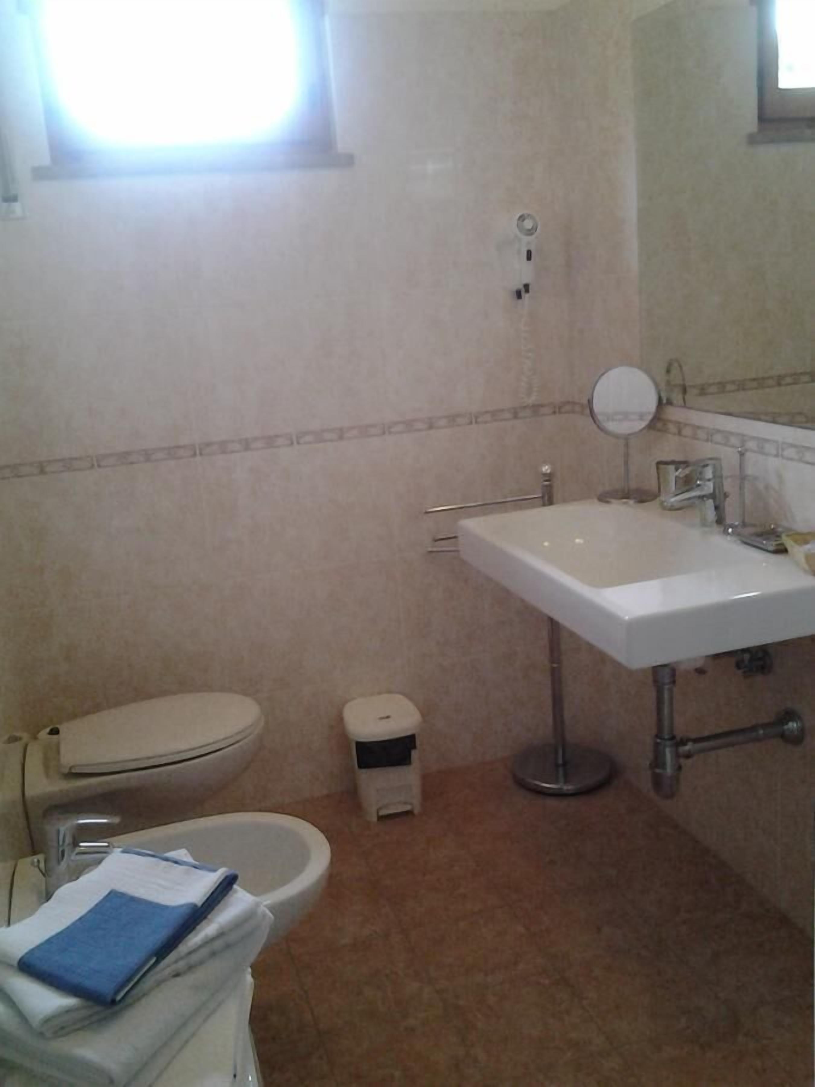 Une salle de bain équipée de toilettes, d’un lavabo et d’une petite poubelle.