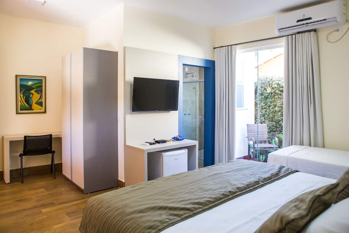 A hotel room with a bed, a desk, a television, a mini-fridge, and a shower.