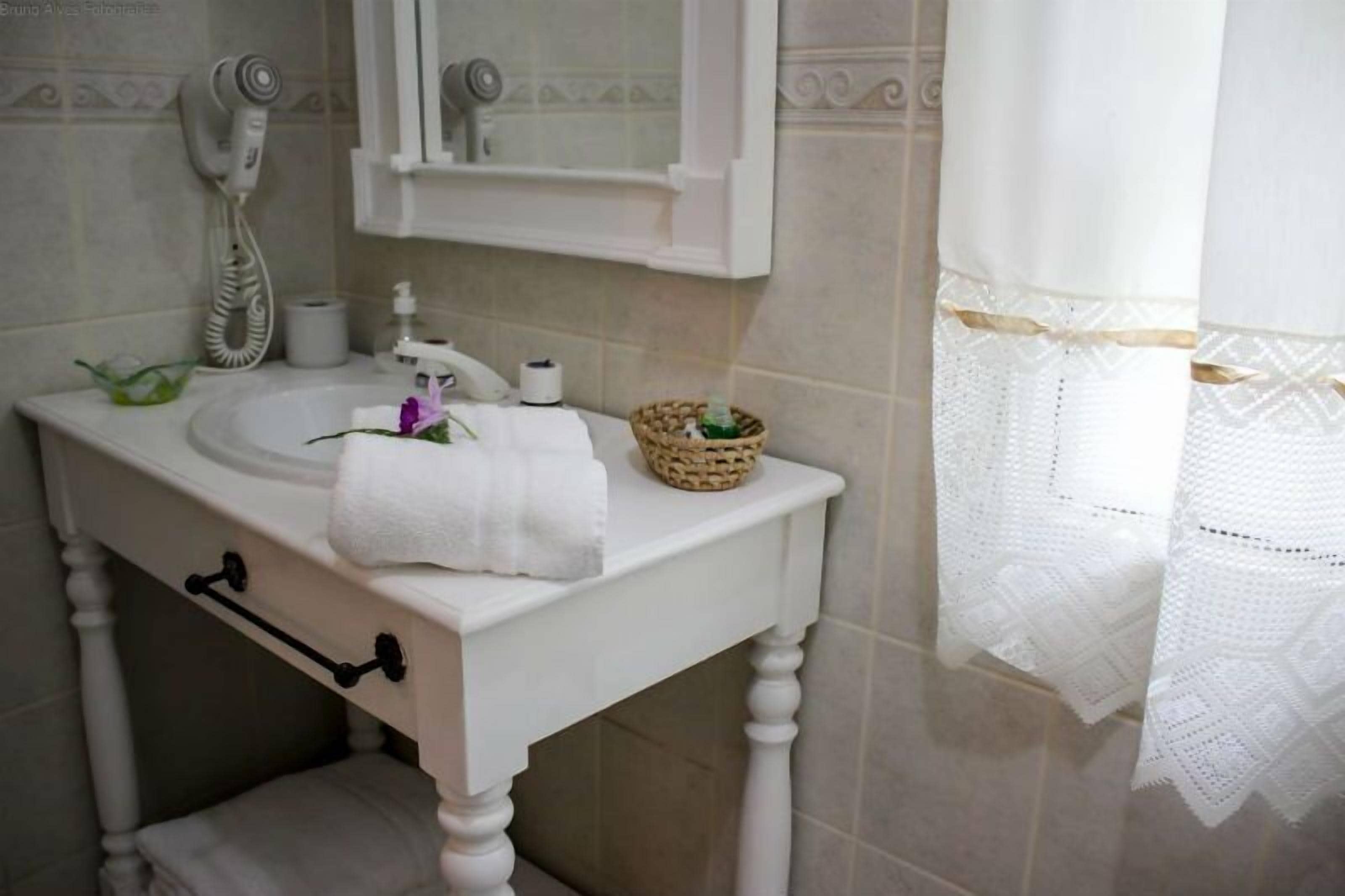 Een badkamer met een witte wastafel, een handdoek, een mand en een handdoekhouder.