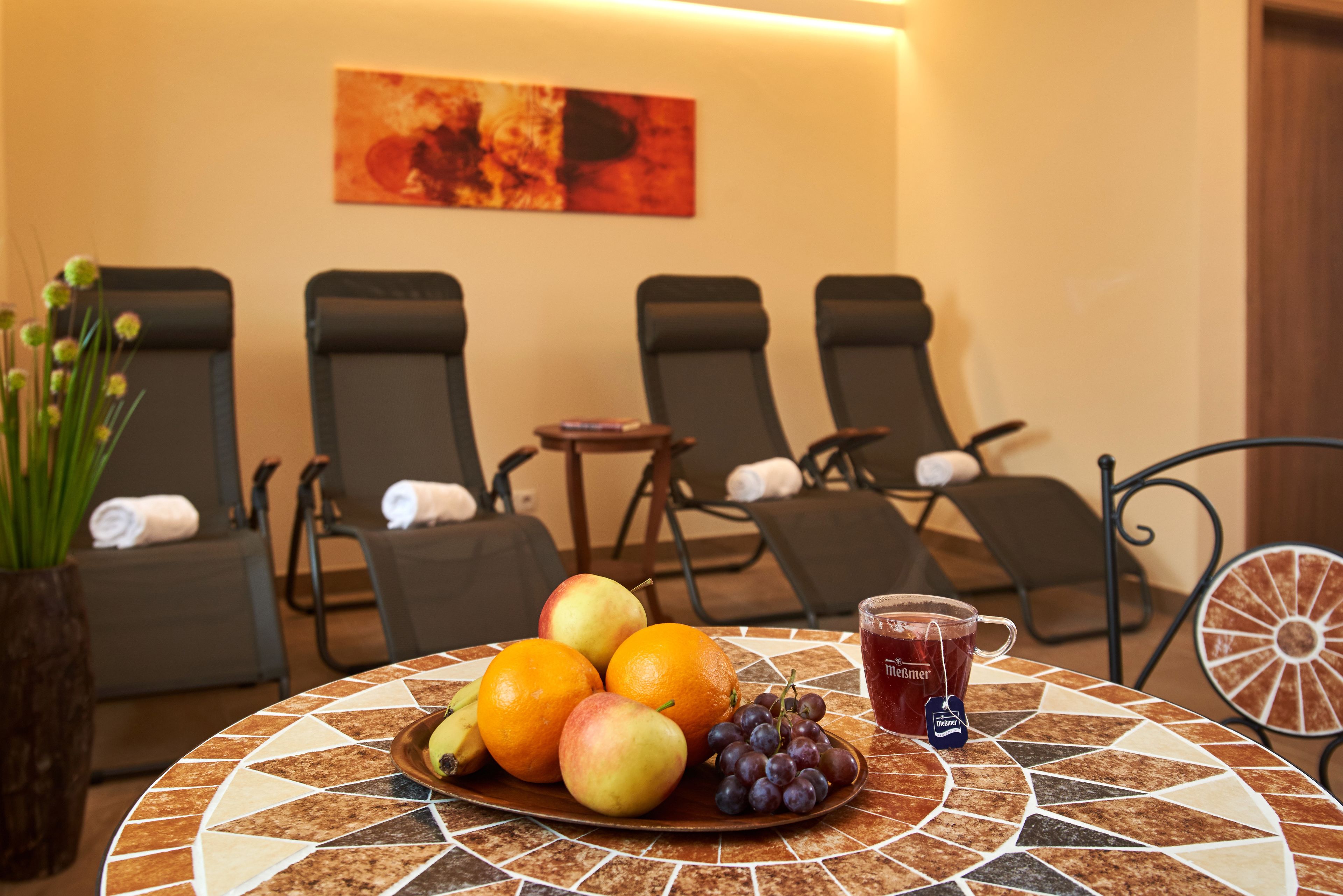 Une table avec une assiette de fruits, un verre de thé glacé et une petite plante.