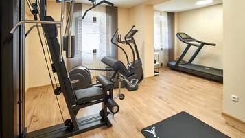 A gym with exercise equipment including a treadmill, elliptical, and weight machines.