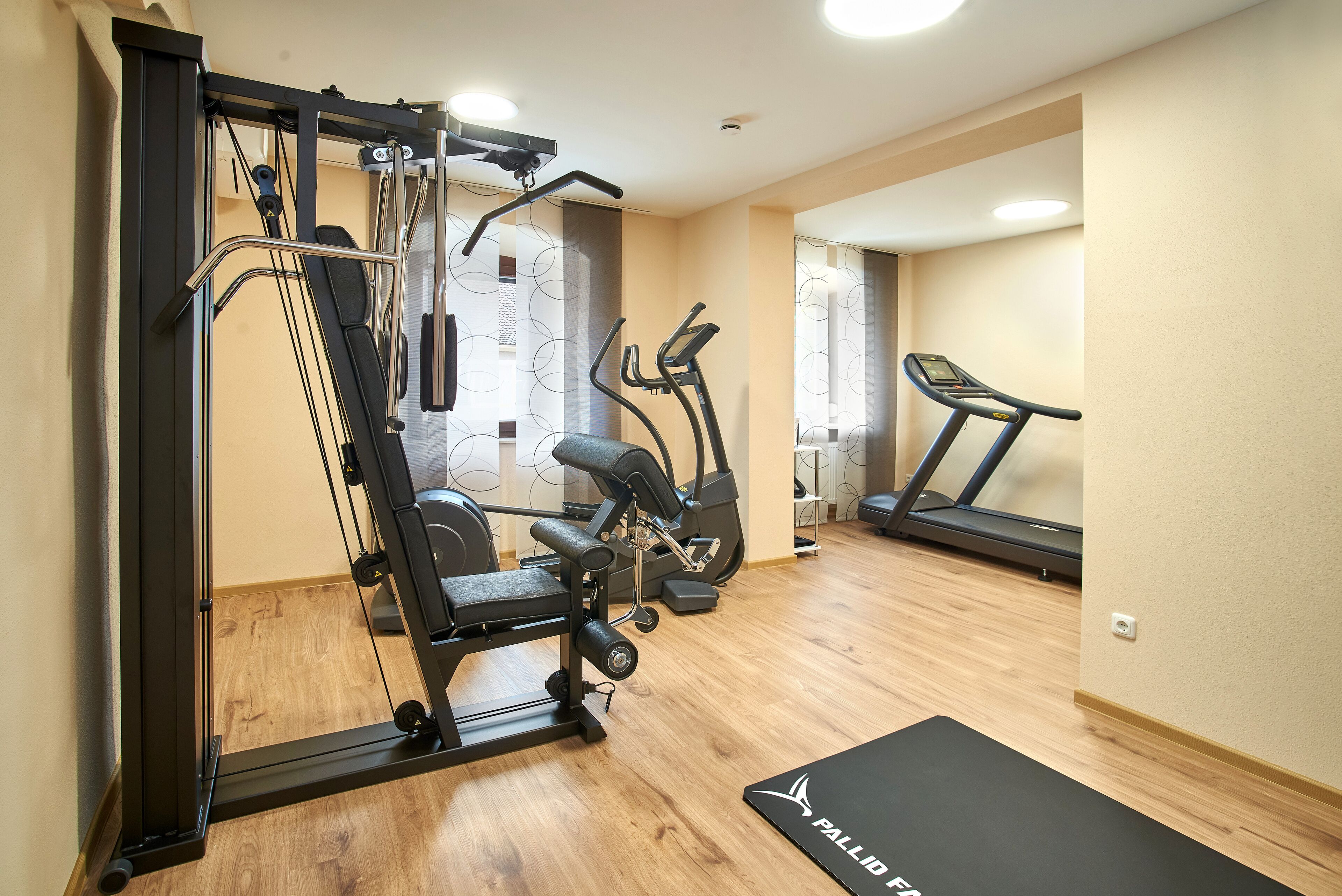 Un gimnasio con barra de dominadas, banco, elíptica y cinta de correr.