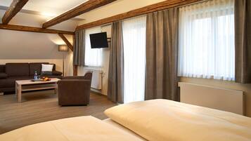 Une chambre d’hôtel avec un lit, un canapé, une table basse et un téléviseur fixé au mur.