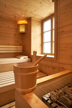 Un sauna en bois avec des bancs, un seau en bois et une fenêtre.