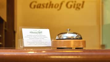 Un'area reception di un albergo con un cartello che riporta 'Gasthof Gigl' e una campanella per il servizio.