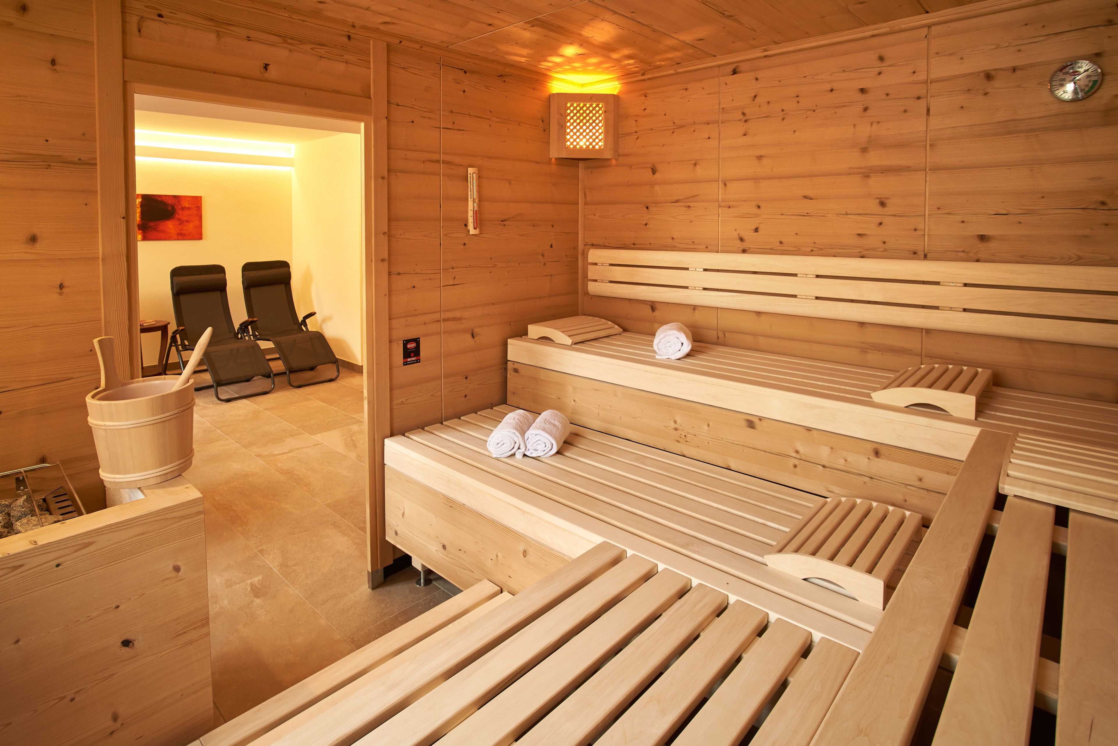 A wooden sauna room with benches and a bench with towels.