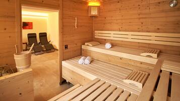 A wooden sauna room with benches and a bench with towels.