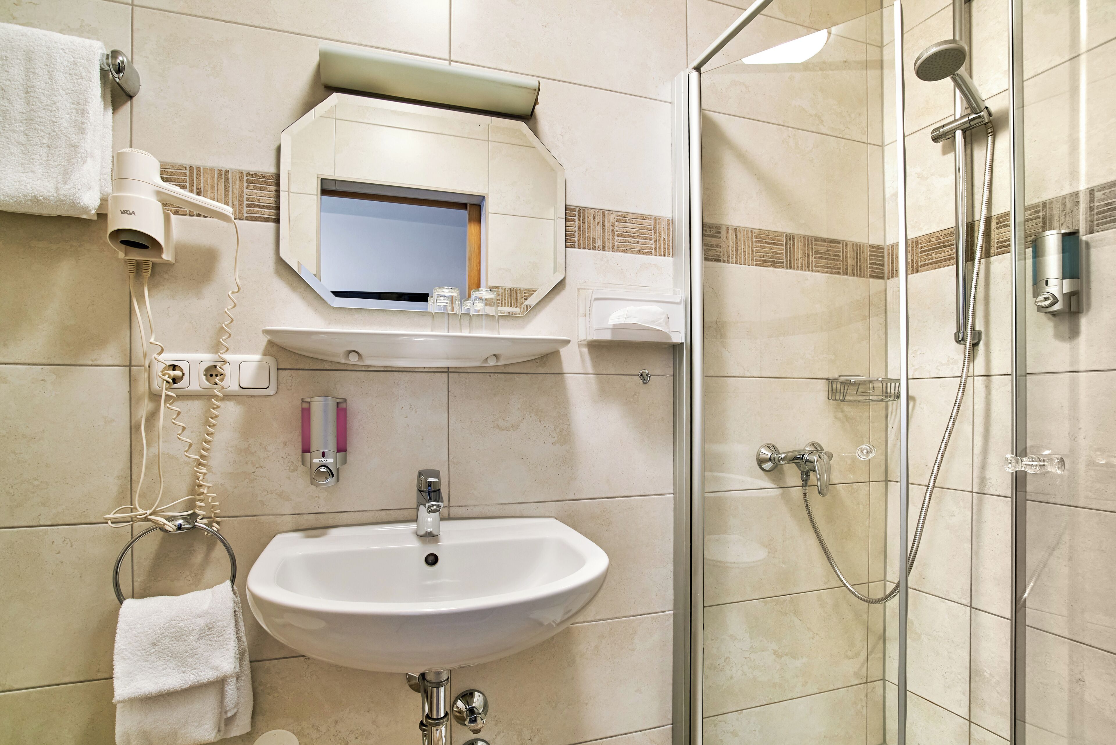 Une salle de bain équipée d’un lavabo, d’un miroir, d’un porte-serviettes et d’une douche.