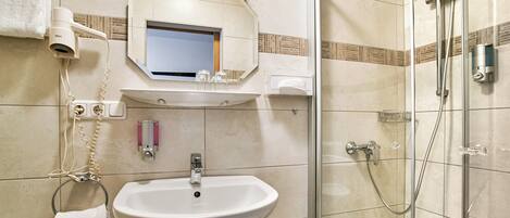Une salle de bain équipée d’un lavabo, d’un miroir, d’un porte-serviettes et d’une douche.