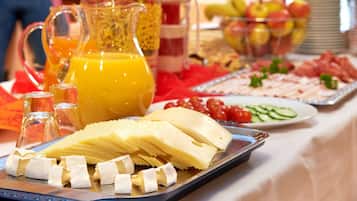 Een buffet met verschillende soorten eten, waaronder kaas, fruit en een karaf sinaasappelsap.