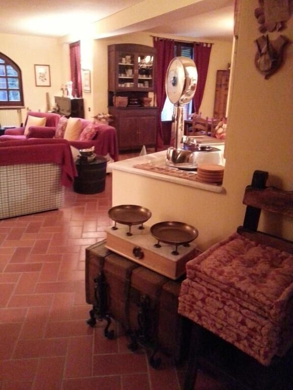 A cozy living room with a fireplace, a dining area with a table set for two, and a kitchen area with a stove and cabinets. - Gli Aceri Bed and Breakfast (Arcola)