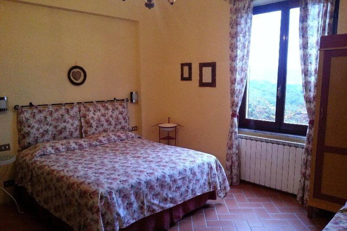 A bedroom with a bed, a small table, and a window with curtains.