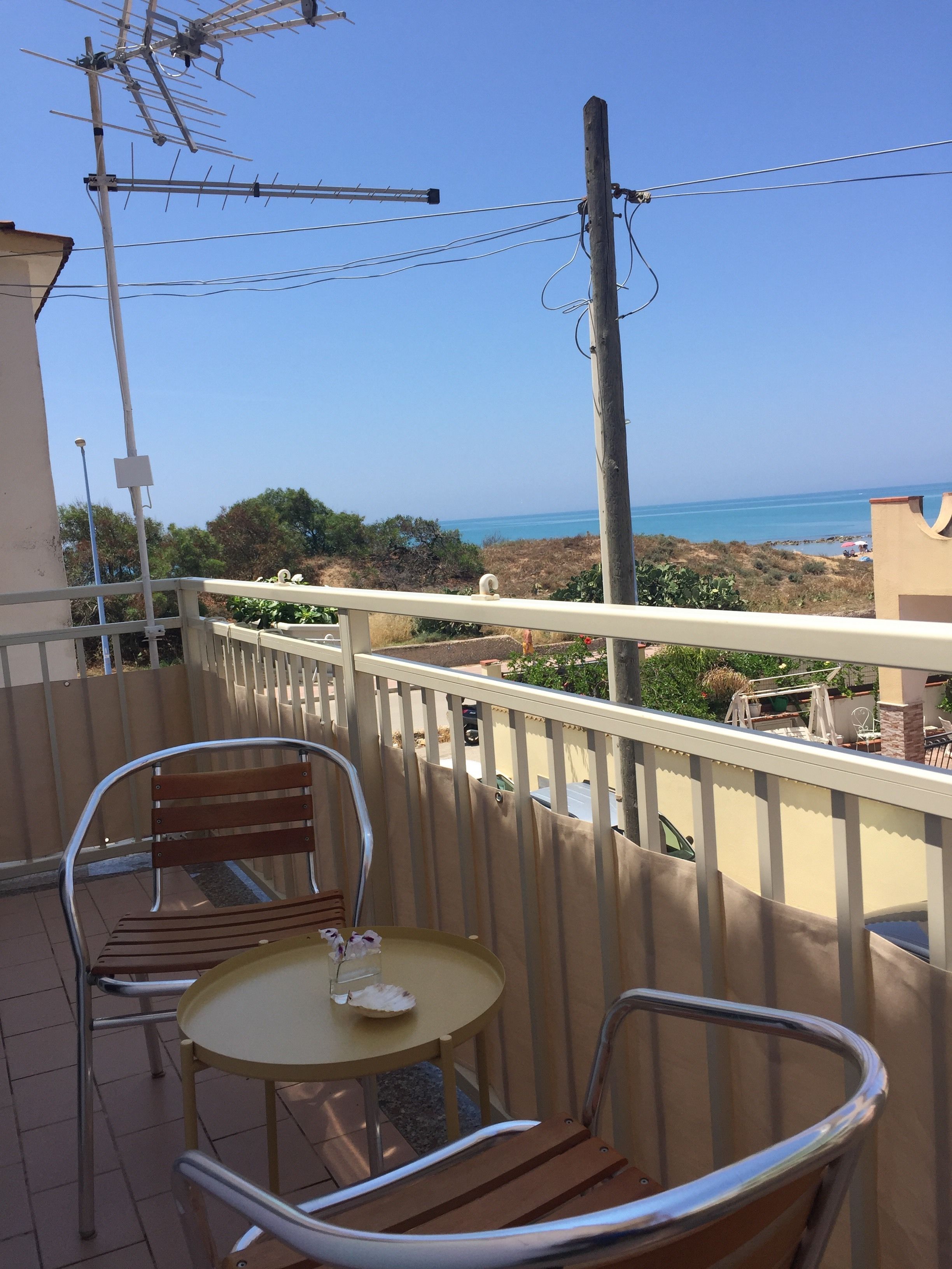 Un balcone con tavolo e sedie, vista sulla costa.