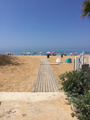 A wooden boardwalk leading to beach umbrellas and beach chairs. - Maribà (Agrigento)