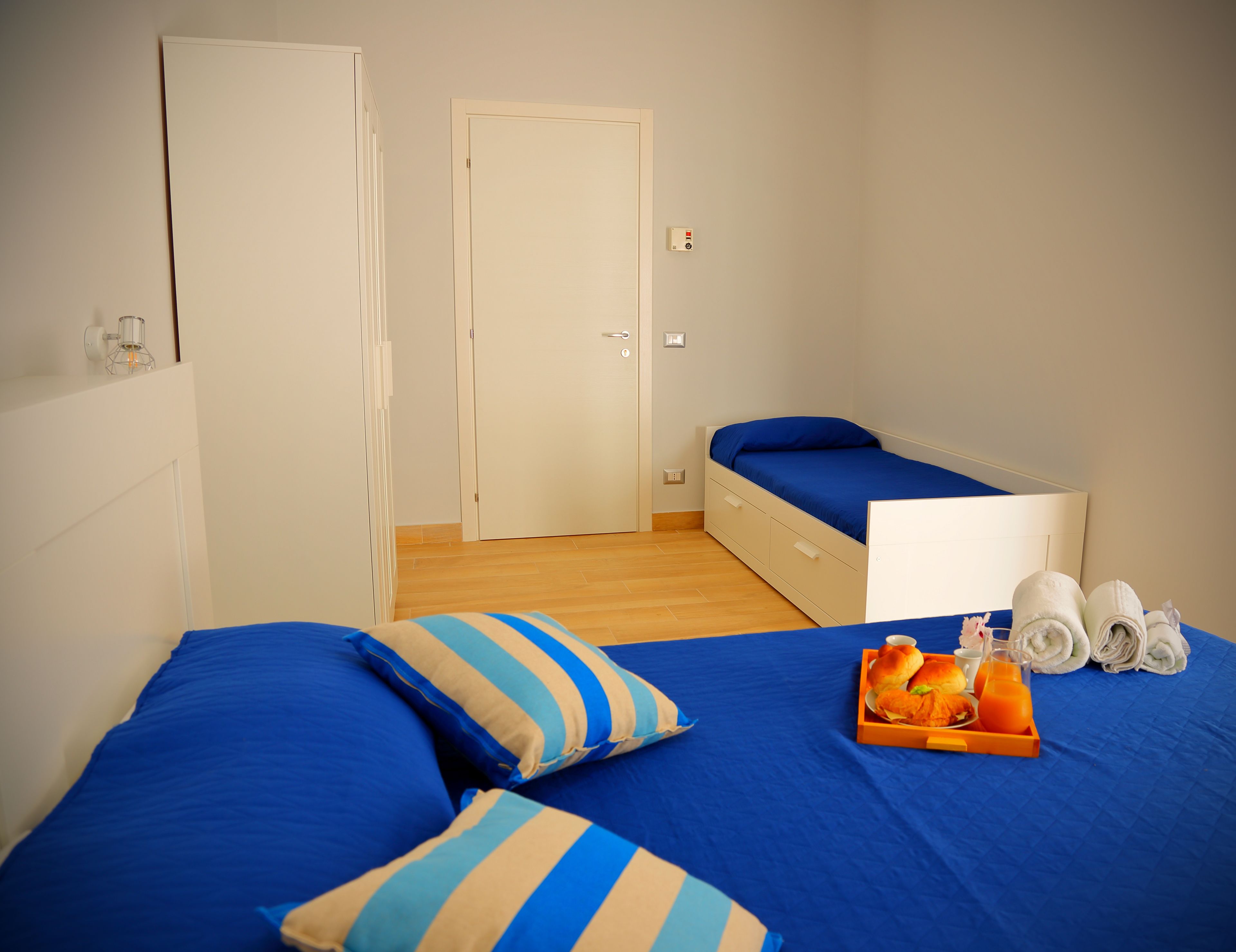Una camera da letto con un letto, un tavolino con asciugamani e un vassoio con cibo, e una porta.