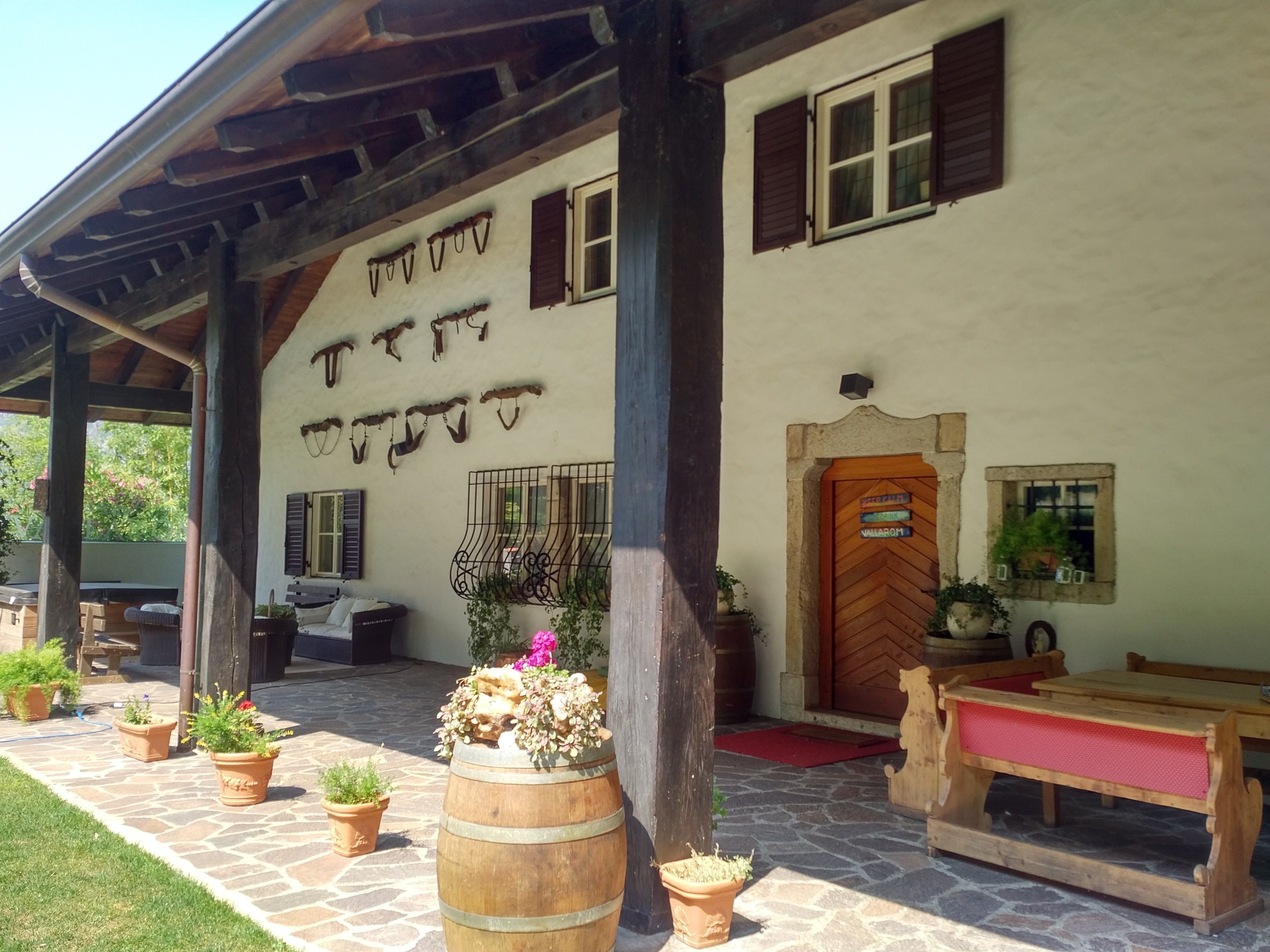 A rustic building with a stone-paved entrance, wooden benches, and potted plants.