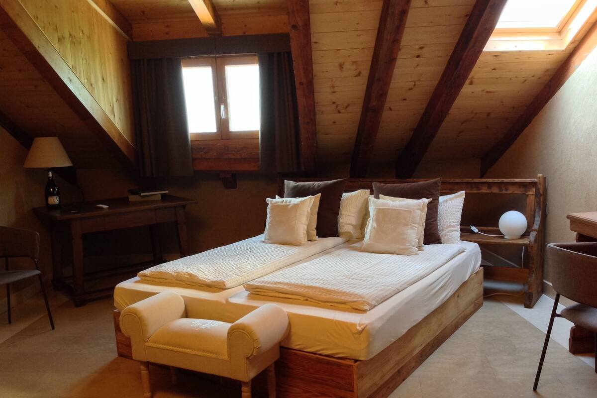 Un dormitorio acogedor en el ático, con una cama de madera, un escritorio y una silla.
