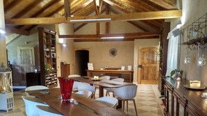 A spacious dining area with a wooden table and white upholstered chairs, a checkered floor, and a rustic wooden ceiling. - Vallarom (Avio)