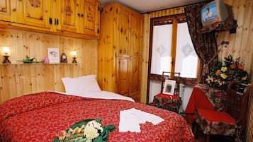 Ein Zimmer mit Holzboden, einem Bett, einem Fernseher und einer Blumenkomposition.