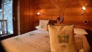 Een houten kamer met een bed, kussens en een nachtkastje met een lamp.