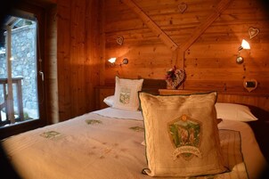 Una habitación de cabaña de madera con una cama, almohadas y una mesita de noche con una lámpara.